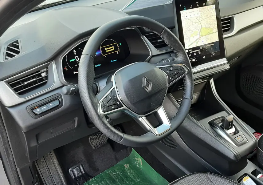 Vue intérieure côté conducteur du Renault Captur 2025, volant multifonction, tableau de bord numérique et écran tactile vertical.