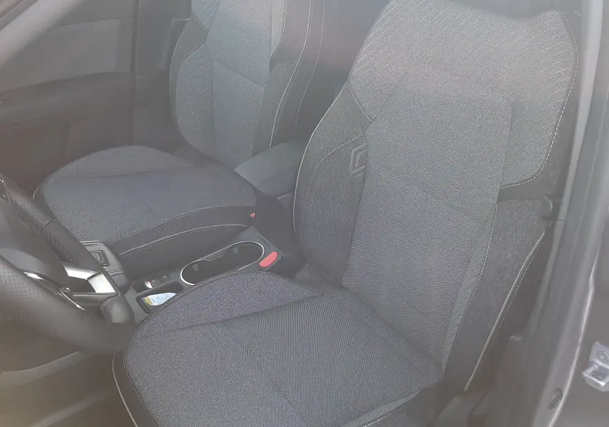 Vue intérieure côté conducteur du Renault Captur 2025, sièges tissu gris foncé avec surpiqûres claires.