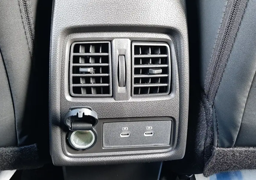 Détail de la console arrière avec bouches d'aération, prise 12V et deux ports USB-C dans un Renault Captur gris Cassiopée.