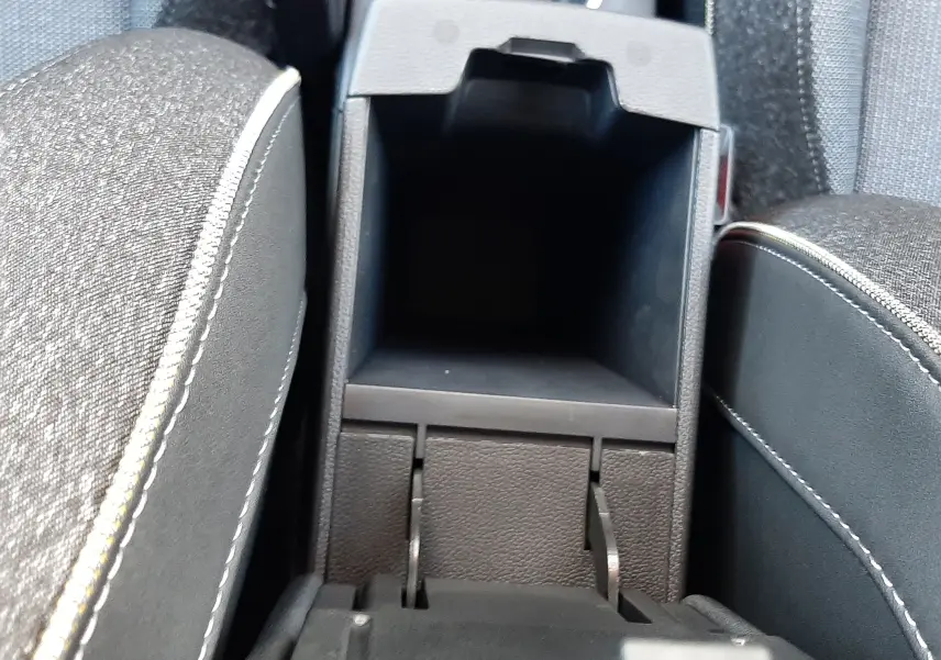 Vue rapprochée de la console centrale ouverte entre les sièges tissu gris du Renault Captur 2025 gris Cassiopée.