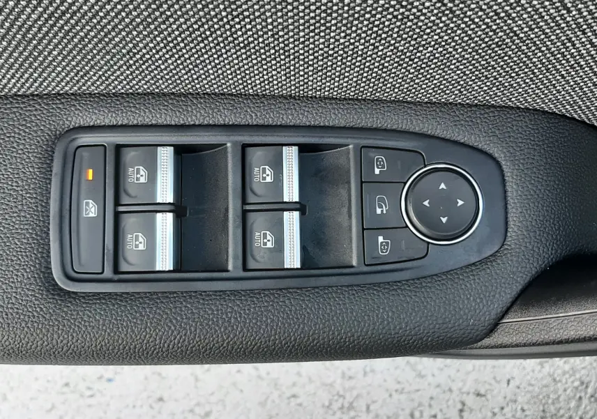 Panneau de commandes des vitres électriques et rétroviseurs sur la portière côté gauche d’un Renault Captur gris Cassiopée.