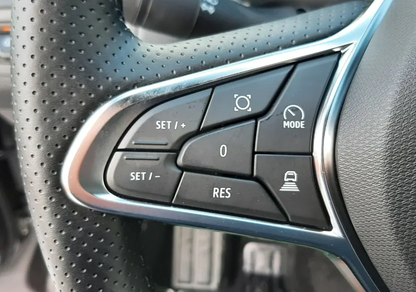Gros plan sur les commandes multifonctions à gauche du volant perforé du Renault Captur gris Cassiopée 2025.