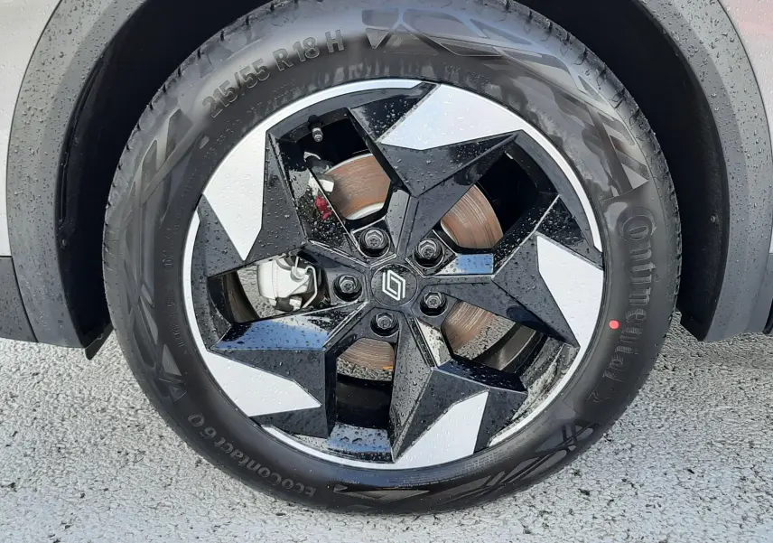 Gros plan sur la roue avant droite du Renault Captur gris Cassiopée, mettant en valeur la jante noire et argentée au design géométrique.