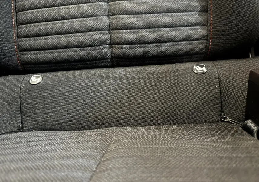 Gros plan sur la banquette arrière noire de la Peugeot 208, montrant les fixations Isofix pour siège enfant.