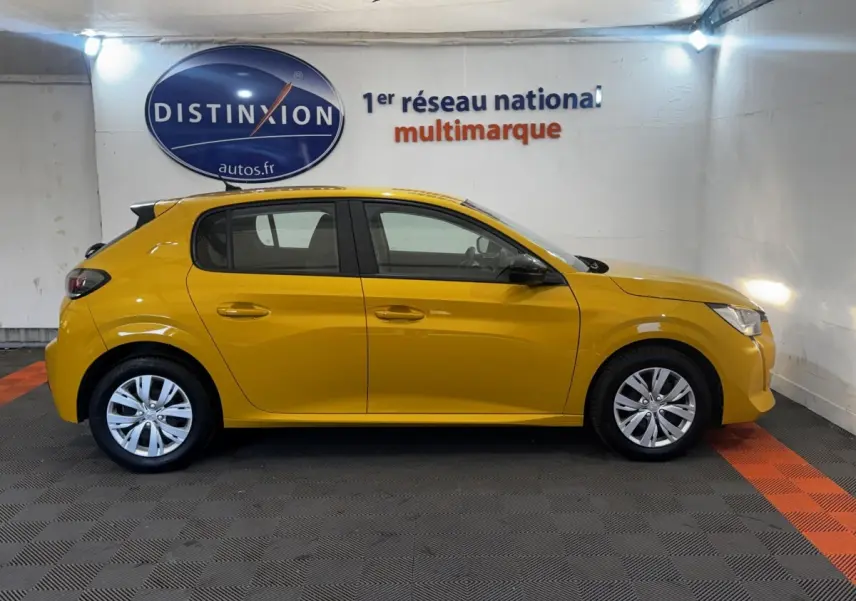 Peugeot 208 jaune vue de profil côté gauche dans un showroom avec sol gris et bandes orange.