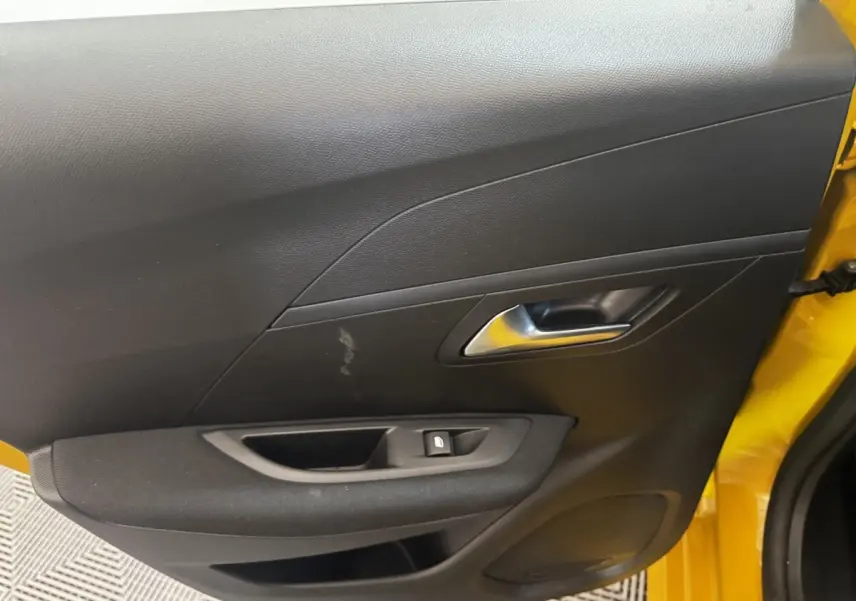 Vue intérieure côté gauche de la porte avant jaune de la Peugeot 208 avec poignée argentée et bouton de verrouillage.