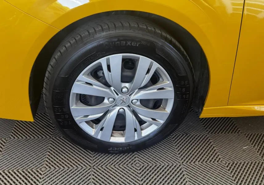 Gros plan sur la roue avant droite d'une Peugeot 208 jaune 2023 avec jante argentée et pneu Dynaxer.