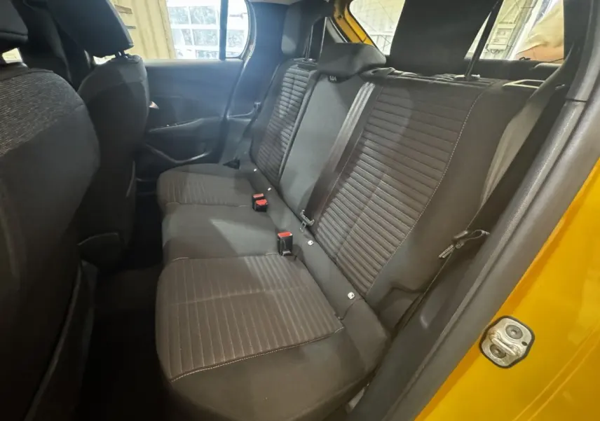 Vue intérieure côté droit des sièges arrière noirs d'une Peugeot 208 jaune 2023, avec ceinture et porte ouvert.