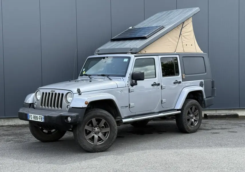 Jeep Wrangler Billet Silver vue 3/4 avant droit avec toit relevable beige et panneau solaire intégré.