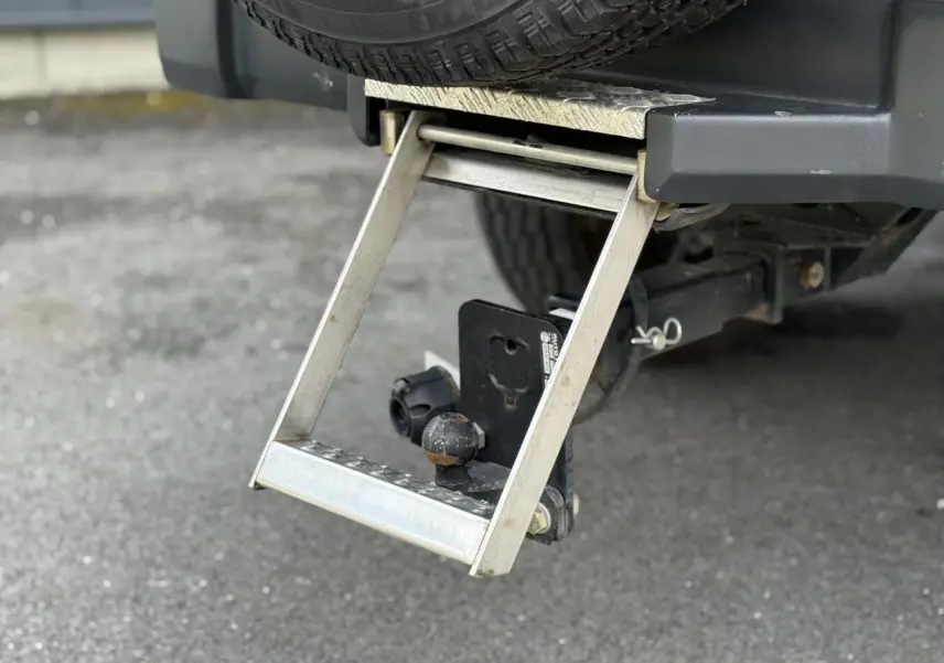 Gros plan sur l'attelage et la marche-pieds arrière du Jeep Wrangler Billet Silver, avec roue de secours visible.