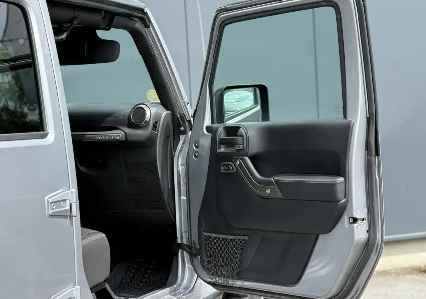 Portière avant droite ouverte d'un Jeep Wrangler Billet Silver 2019, montrant l'intérieur noir côté passager.