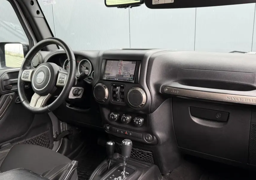 Intérieur avant du Jeep Wrangler 2019, tableau de bord noir avec écran GPS et volant multifonction visible côté gauche.