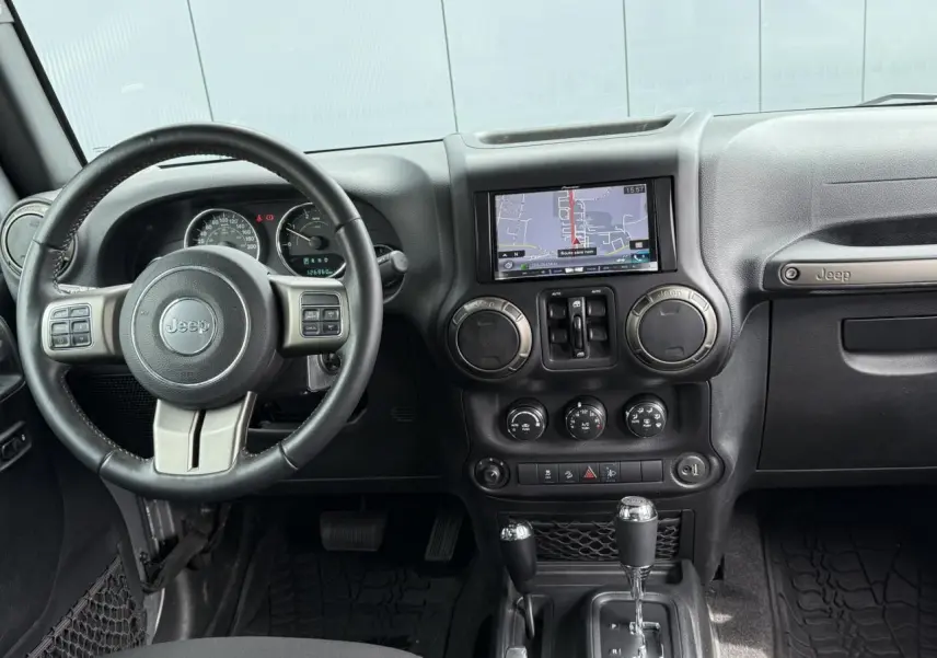 Intérieur de Jeep Wrangler 2019 vu de face, tableau de bord noir avec écran GPS et volant multifonction Jeep.
