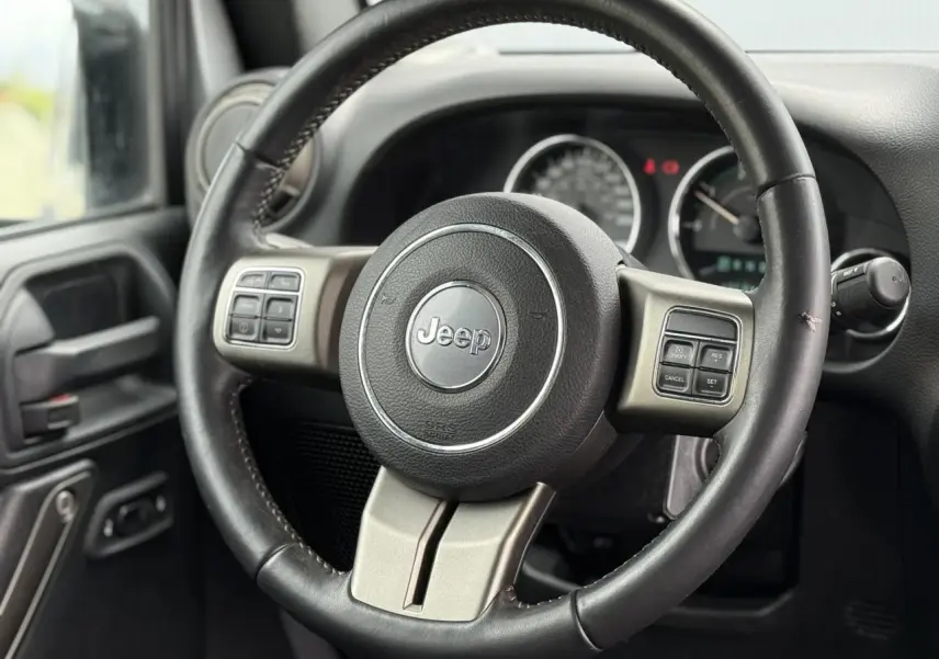 Volant multifonction Jeep Wrangler 2019 en cuir noir, vue rapprochée côté conducteur avec tableau de bord flou.