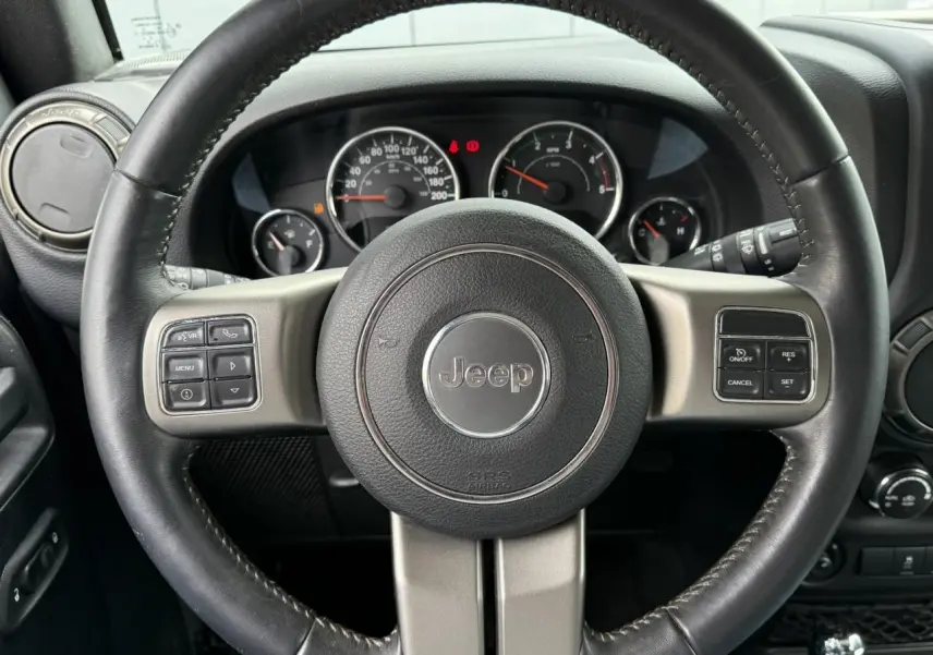 Volant cuir Jeep avec commandes multifonctions, tableau de bord et compteurs visibles en arrière-plan intérieur Wrangler 2019.