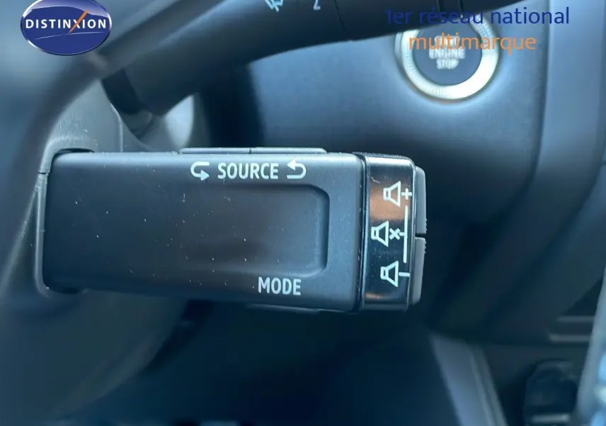 Gros plan sur la commande au volant du Renault Captur E-Tech blanc nacré, avec bouton source et mode visibles.