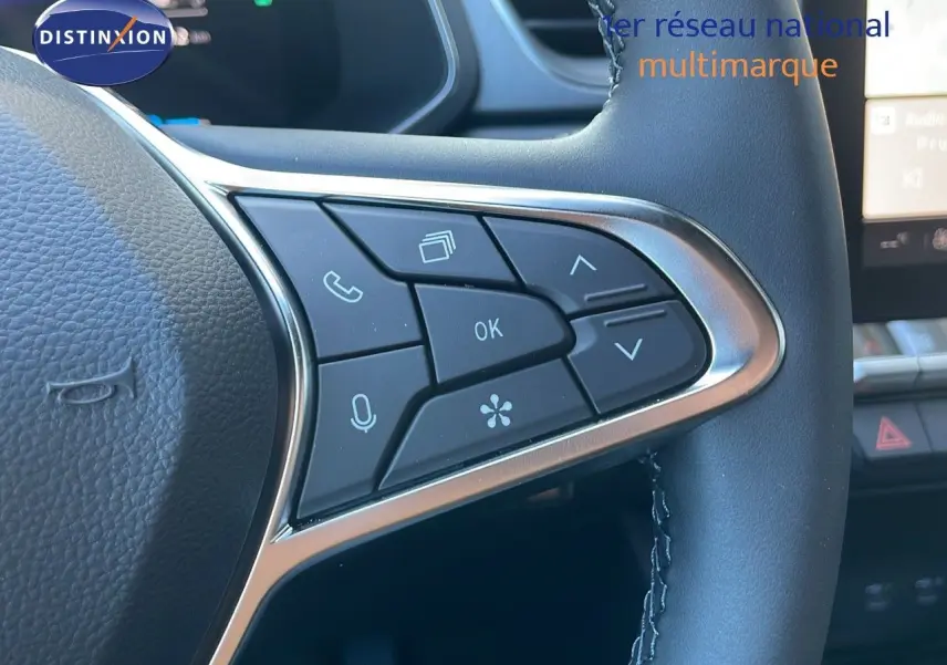 Gros plan sur les commandes au volant en cuir noir du Renault Captur E-Tech blanc nacré, mettant en valeur les boutons multifonctions.