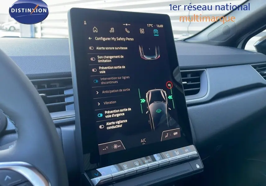 Vue rapprochée de l'écran tactile central du tableau de bord du Renault Captur blanc nacré avec toit noir, affichant les aides à la conduite.