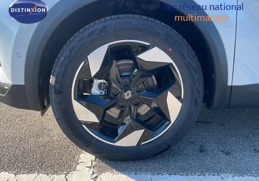 Gros plan sur la roue avant gauche du Renault Captur blanc nacré avec jante noire et argentée à design étoilé.