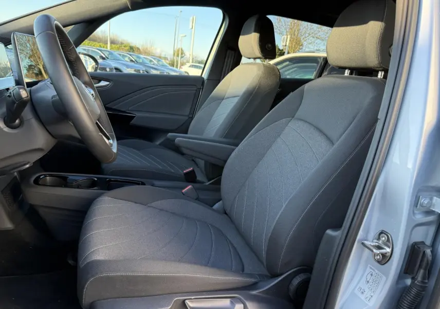 Vue intérieure côté conducteur du Volkswagen ID.3 Pro S 2025 gris argent, sièges tissu gris et volant multifonction.
