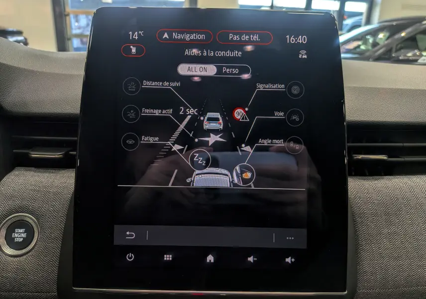 Écran tactile central de la Renault Clio V rouge Flamme affichant les aides à la conduite avec interface moderne.