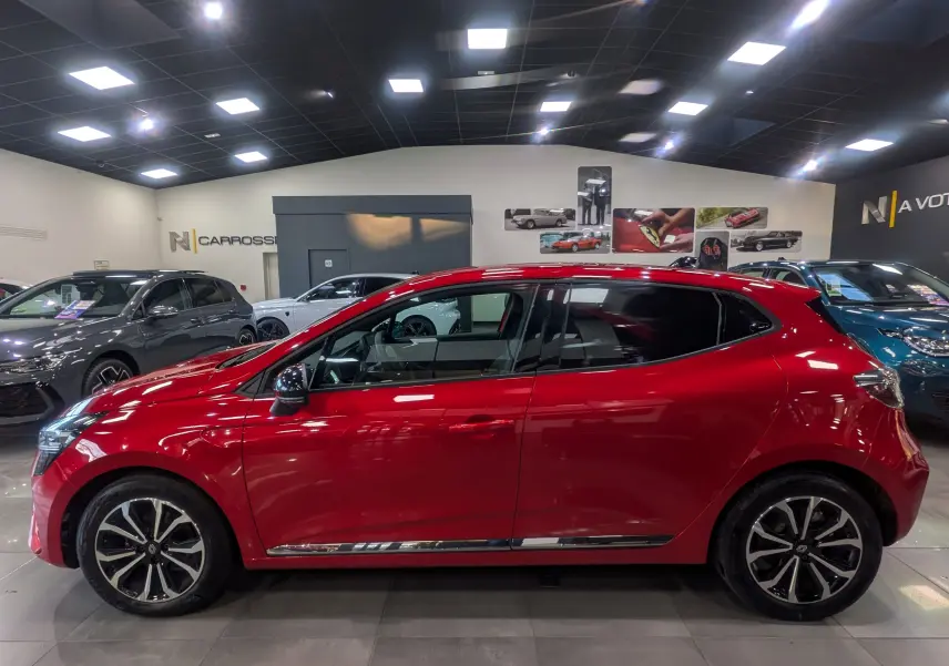 Profil latéral droit de la Renault Clio V Rouge Flamme, avec jantes alliage et détails chromés sous les portes.