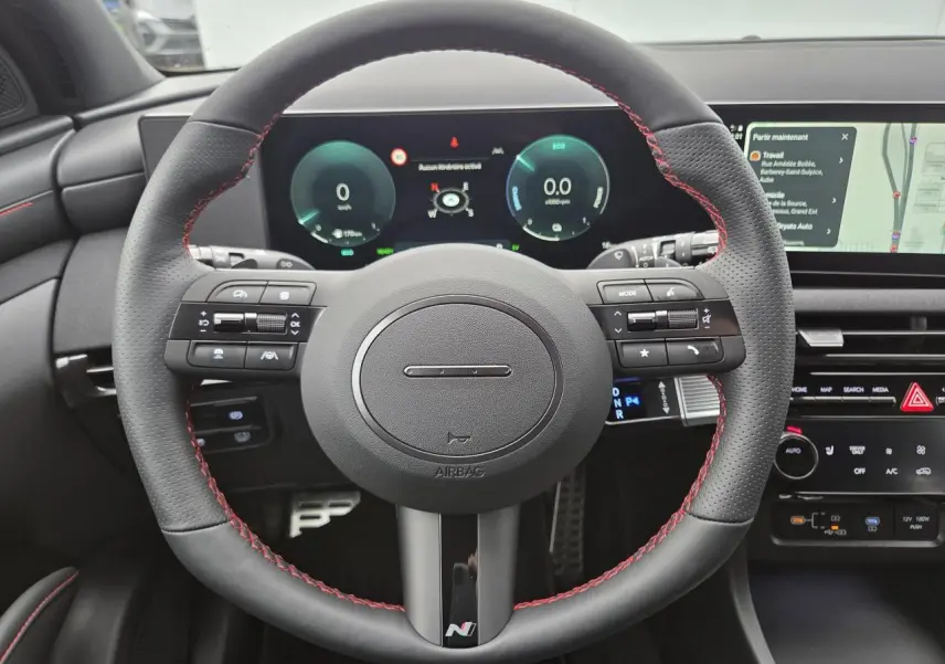 Vue frontale du volant sport cuir noir avec surpiqûres rouges et tableau de bord numérique du Hyundai Tucson N Line 2025.