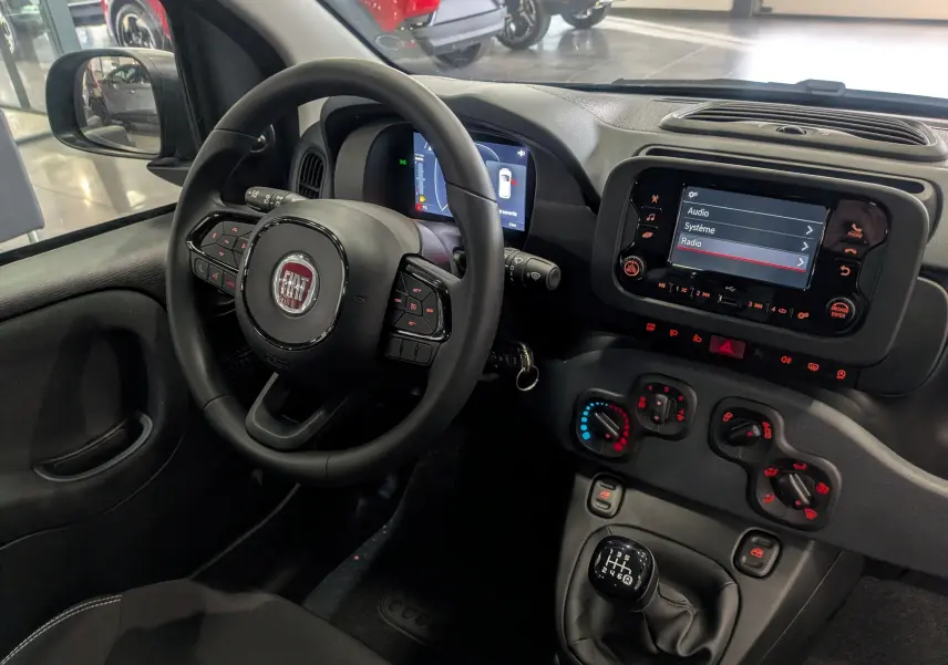 Vue intérieure côté conducteur de la Fiat Panda 1.0 Hybrid 2025, volant multifonction et tableau de bord avec écran tactile.