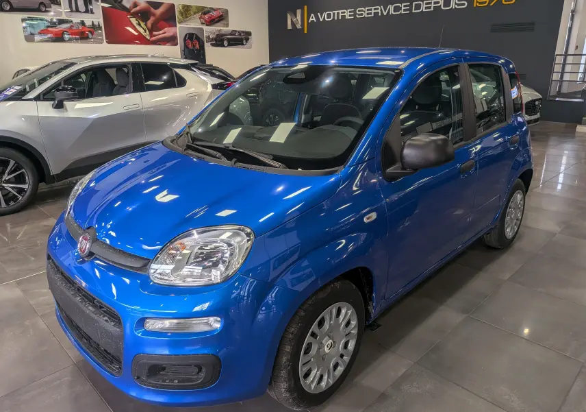 Vue 3/4 avant droite d'une FIAT Panda 1.0 Hybrid City bleu Italia en showroom avec jantes acier et rétroviseurs noirs.