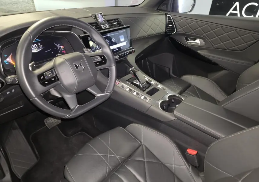 Intérieur noir du DS7 E-Tense 2024 vu côté conducteur, avec volant cuir, tableau de bord numérique et console centrale moderne.