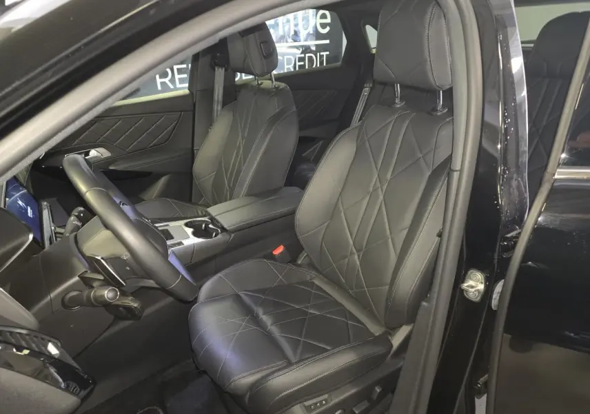 Vue intérieure côté conducteur du DS7 Crossback E-Tense 225 Rivoli noir, sièges cuir noir matelassé et console centrale visible.