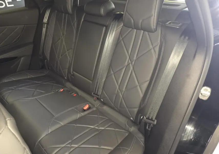 Vue intérieure des sièges arrière en cuir noir matelassé du DS7 Crossback E-Tense 2024, avec ceinture de sécurité et porte ouvert.