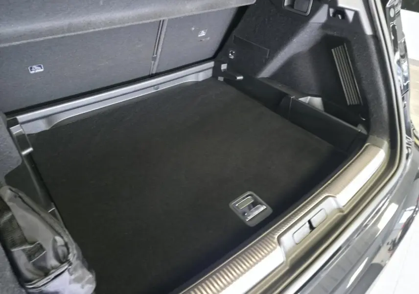 Coffre ouvert vu de trois quarts arrière droit du DS7 Crossback noir avec seuil de coffre chromé et tapis noir.