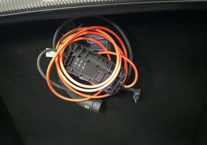 Câble de recharge orange enroulé dans le coffre noir du DS7 Crossback E-Tense 2024.