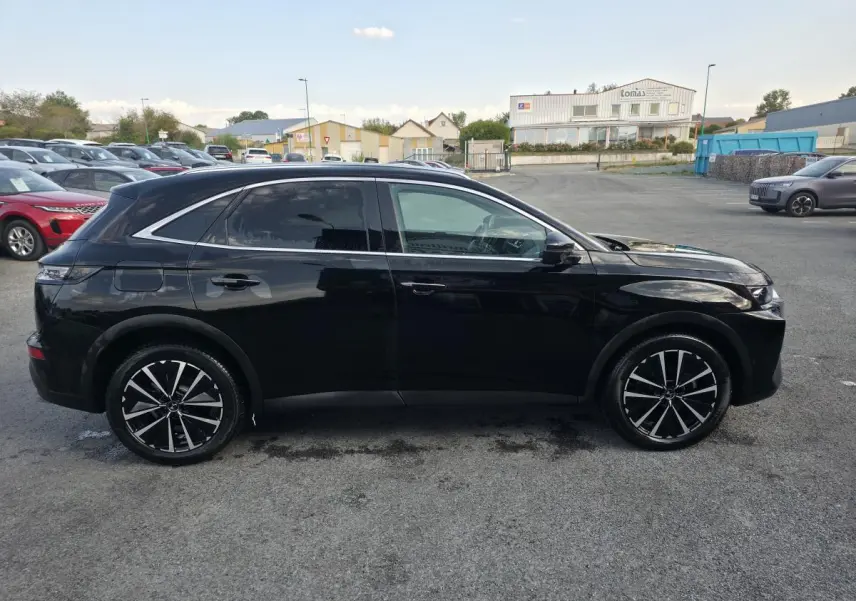 Vue latérale droite du SUV DS7 Crossback E-Tense 225 noir avec jantes alliage 19 pouces sur parking extérieur.
