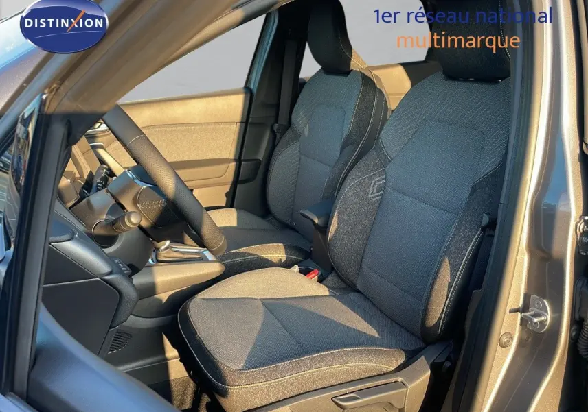 Intérieur avant du Renault Captur E-Tech gris cassiopée, sièges tissu noir et gris, volant et console visibles côté conducteur.