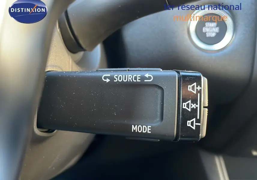 Gros plan sur la commande au volant du Renault Captur gris cassiopée, avec bouton source et mode, et démarrage sans clé visible.