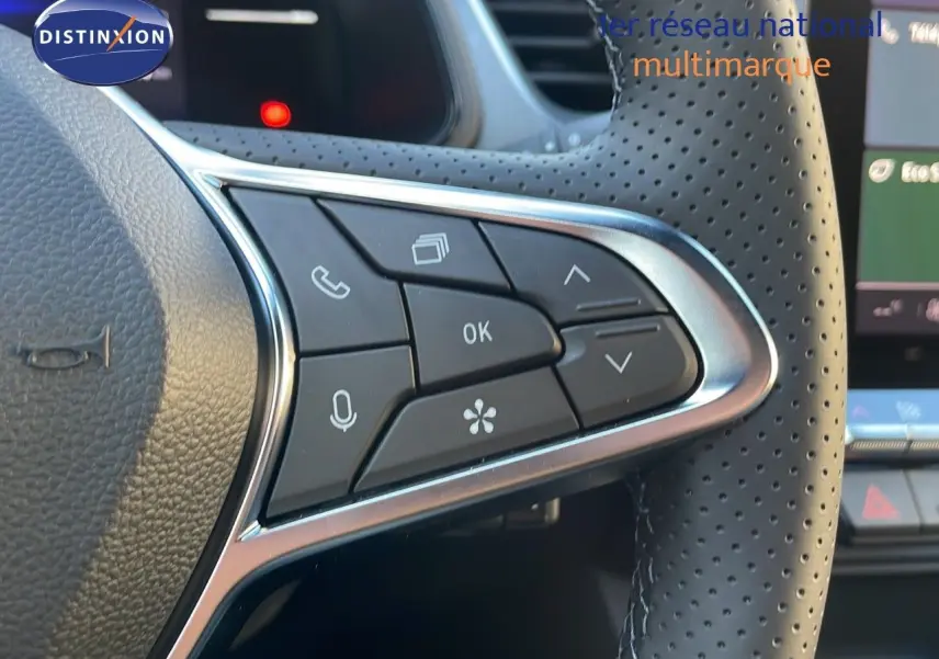 Gros plan sur les commandes multifonctions du volant perforé du Renault Captur gris Cassiopée 2025 hybride.