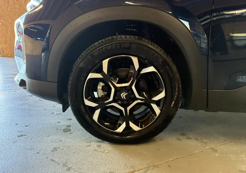 Gros plan sur la roue avant gauche du Citroën C5 Aircross bleu Eclipse Métal avec jante alliage bicolore distinctive.