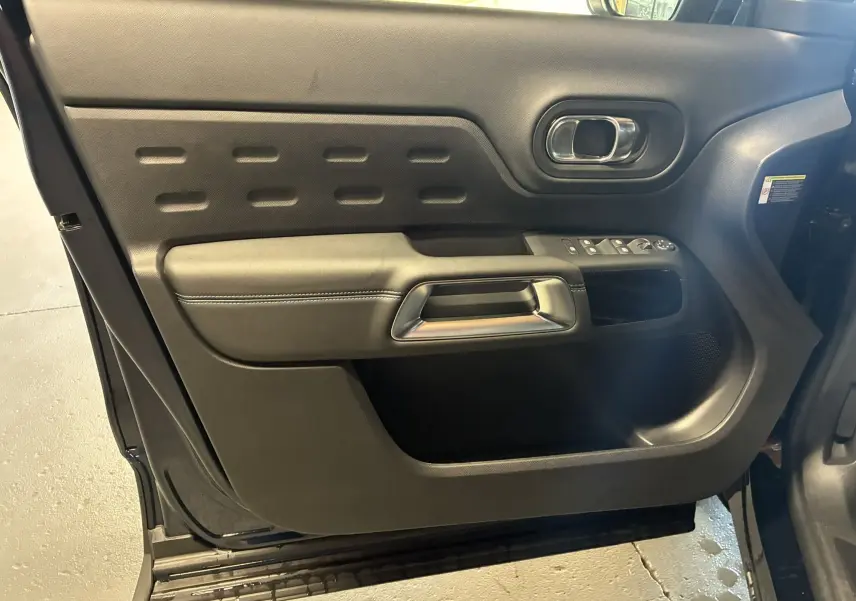 Vue intérieure de la porte avant gauche du Citroën C5 Aircross bleu Eclipse Métal, avec poignée argentée et commandes de vitres.