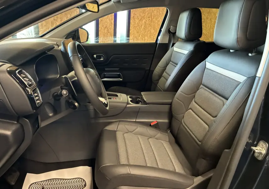 Intérieur avant du Citroën C5 Aircross 2025 avec sièges cuir noir et tissu gris, vue côté conducteur ouverte.