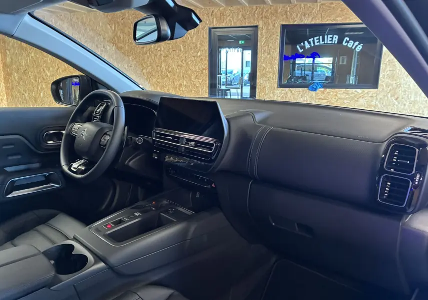 Intérieur noir du Citroën C5 Aircross 2025, vue côté conducteur sur tableau de bord et console centrale moderne.