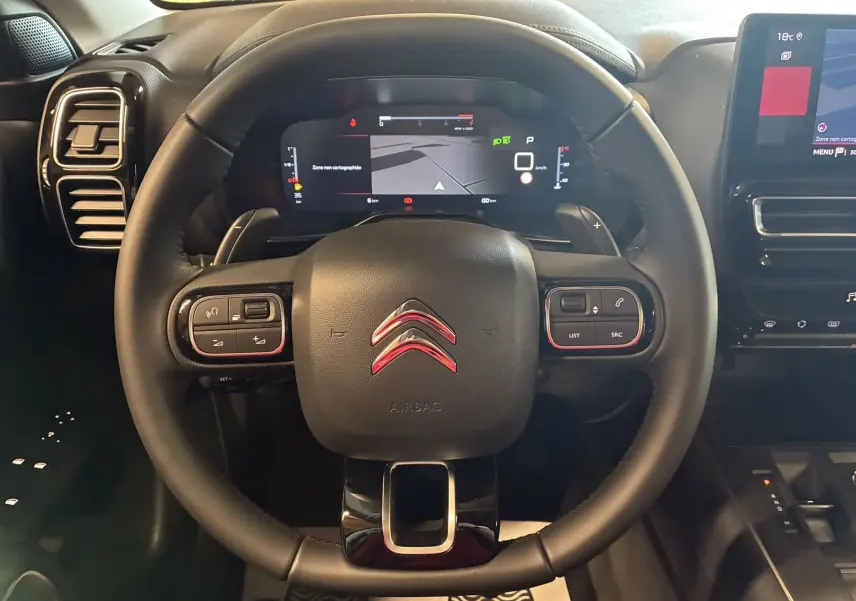 Vue rapprochée du volant cuir noir du Citroën C5 Aircross 2025 avec tableau de bord numérique et écran tactile central.