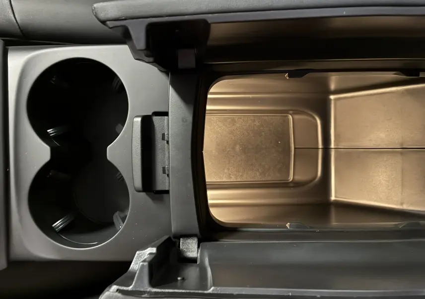 Vue rapprochée de la console centrale ouverte du Citroën C5 Aircross 2025, montrant les porte-gobelets et le rangement intérieur.