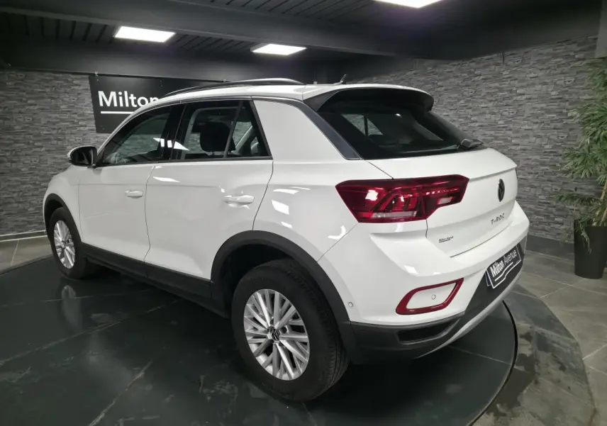 Volkswagen T-Roc blanc vu en 3/4 arrière droit, avec jantes alliage et feux arrière LED rouges.