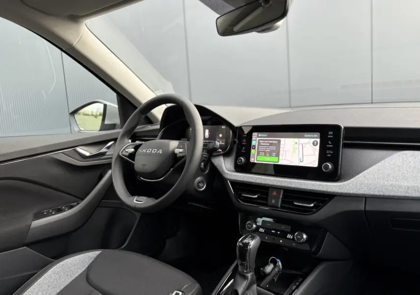 Intérieur du Skoda Kamiq 2025 vu côté conducteur, tableau de bord gris avec écran tactile et volant multifonctions.