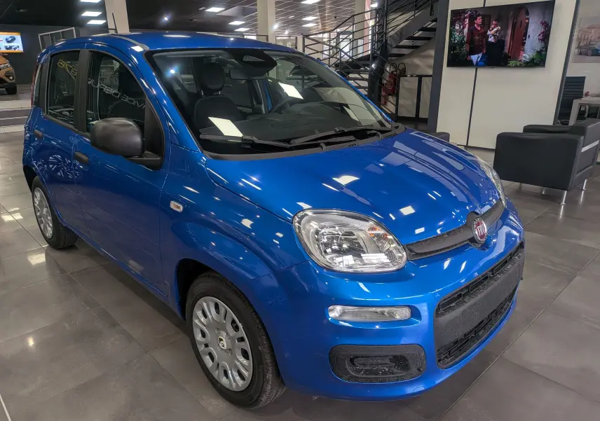 Fiat Panda 1.0 Hybrid City bleu Italia vue 3/4 avant droit en intérieur showroom, avec jantes acier et rétroviseurs noirs.