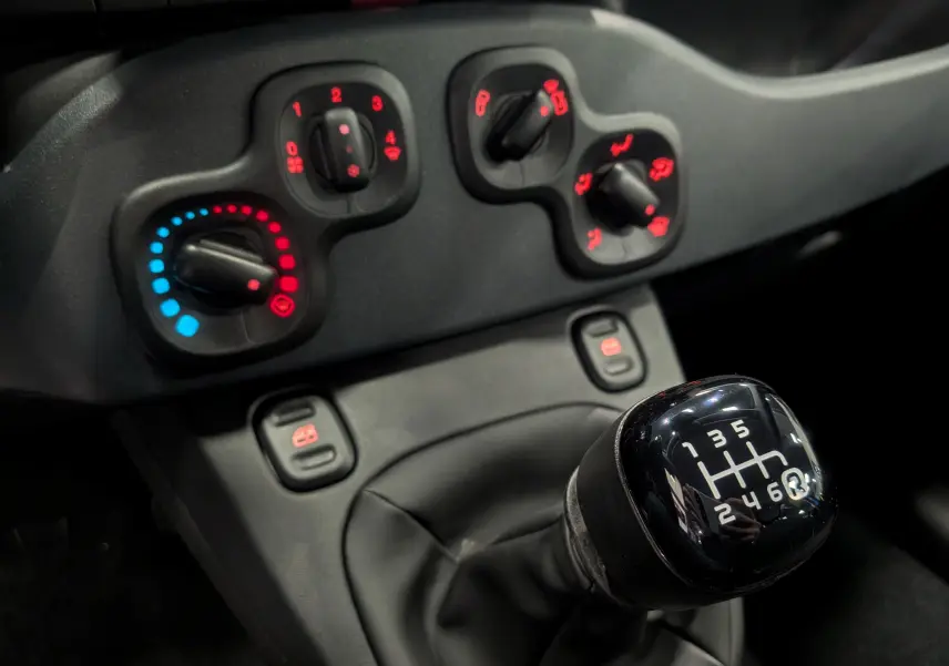 Gros plan sur le levier de vitesses manuel 6 rapports de la Fiat Panda 1.0 Hybrid, avec commandes de climatisation en arrière-plan.