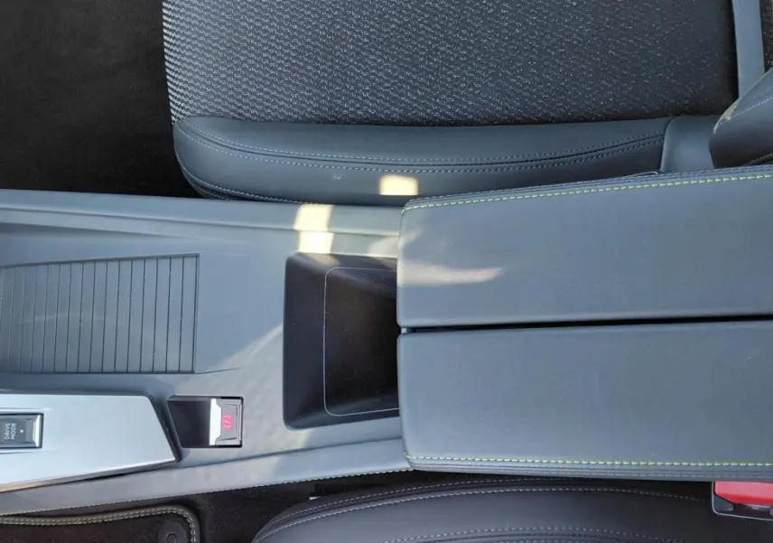 Vue plongeante sur l'accoudoir central gris avec surpiqûres vertes et console centrale de la Peugeot 308 Hybrid 145 e-DCS6 GT.
