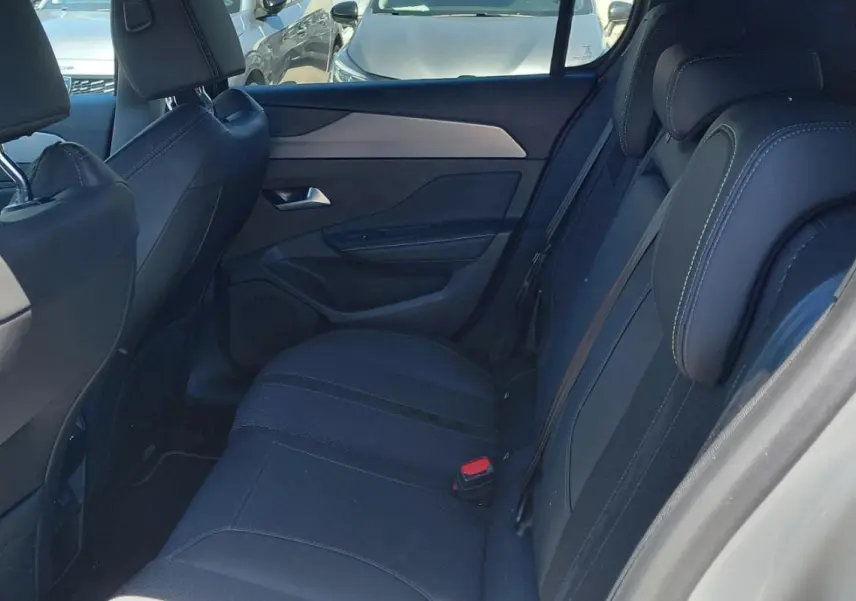 Vue intérieure côté droit des sièges arrière noirs avec surpiqûres vertes d'une Peugeot 308 Hybrid 145 e-DCS6 GT gris 2025.